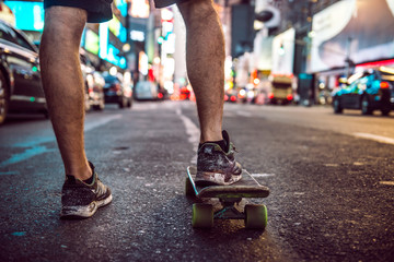 Man riding on skateboard in New York City street at the night. Male legs with skateboard in night city. © Nick Starichenko