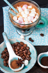 Coffee cup with sugar and spices on a wooden board.