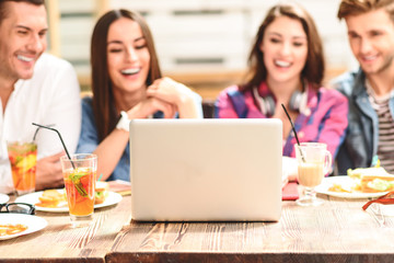 Four friends in coffee shop using laptop