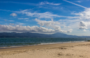 Praia e céu azul com nuvens.
