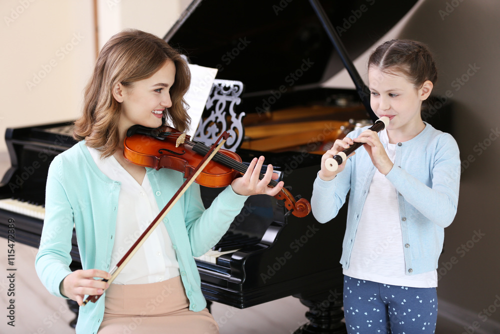 Canvas Prints Two girls playing violin and flute on piano background