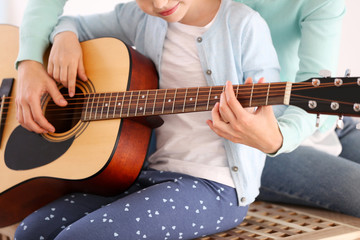 Small girl learning play guitar with teacher
