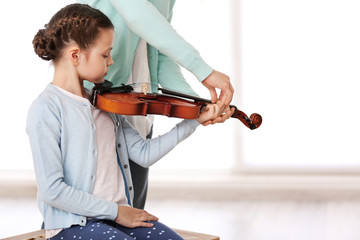 Small girl learning play violin with teacher