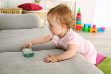 Baby with bottle on sofa in room