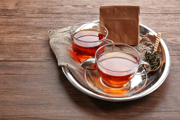 Glass cups of tea in silver tray on wooden table
