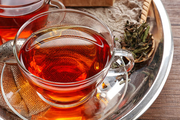 Glass cup of tea in silver tray on wooden table