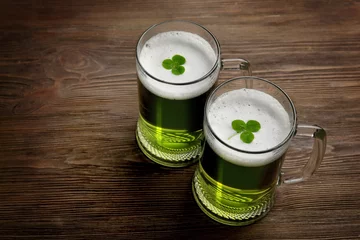 Foto op Canvas Glasses of green beer with clover leaves on wooden background © Africa Studio