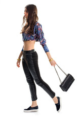 Woman wears floral crop top. Slip ons and quilted purse. Fashion model in casual clothes. New spring collection.