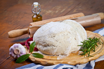 Pizza dough with ingredients on the wooden table