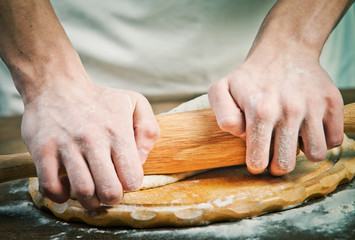 Making dough by mens hands on wooden table background
