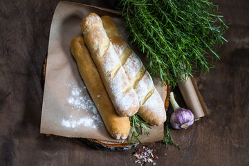 Homemade baguette with Rosemary on rustic wooden background