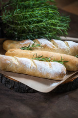 Homemade baguette with Rosemary on rustic wooden background
