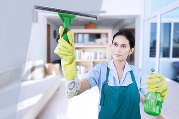 Young maid cleaning the mirror