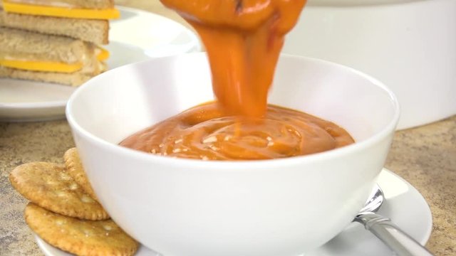 Ladling tomato bisque into a bowl, slow motion
