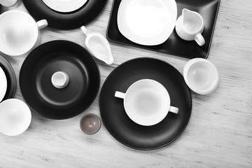 Black and white empty dishes on white wooden background.