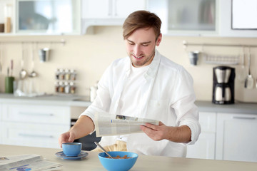 Young handsome man with cup of coffee in the kitchen