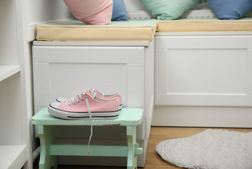 Pink female sneakers beside nook furniture