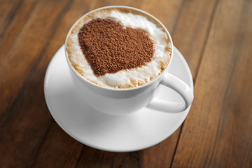 Cup of coffee with creative pattern on wooden table