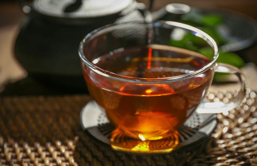 Traditional eastern tea ceremony with teapot and teacup on wicker mat