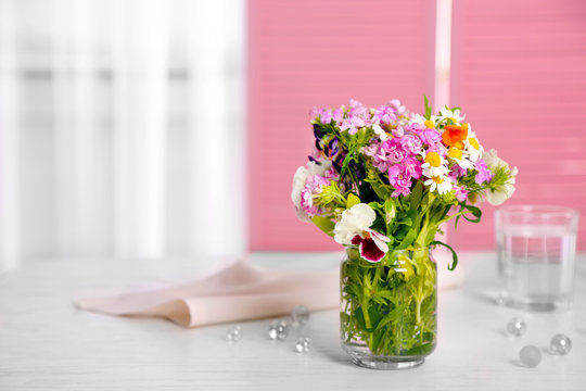 Meadow flowers bouquet in glass vase on table