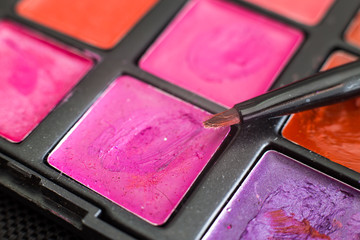 Makeup brushes on colorful cosmetics.