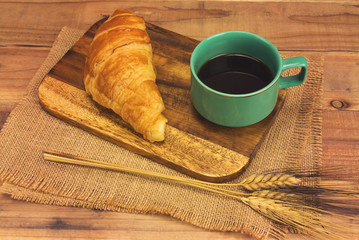 A cup of strong black espresso coffee and fresh croissant