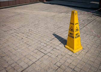 A yellow plastic cone warning of a wet floor