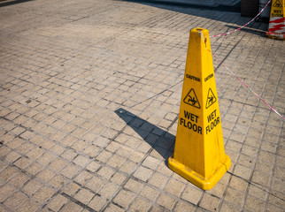 A yellow plastic cone warning of a wet floor