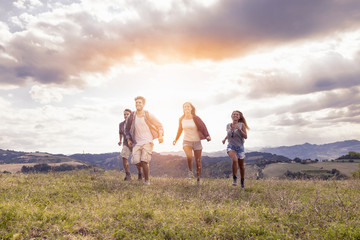 group of young hikers walking toward the horizon over the mounta