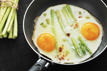 scrambled eggs in a frying pan with asparagus