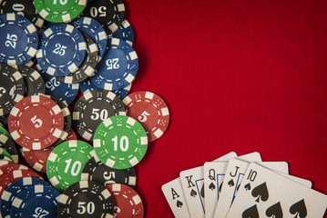 Gambling chips and card for poker on red felt background