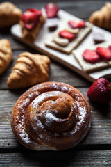 delicious breakfast with strawberries and sweet bun on wooden background. Fruit, food, chocolate