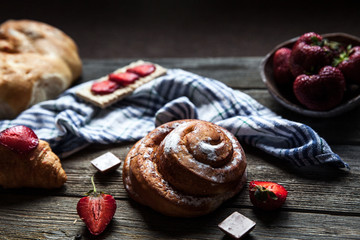 delicious breakfast with strawberries and sweet bun on wooden background. Fruit, food, chocolate