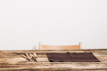 Craftsman workplace, white background, free space. Front view on wooden table with pottery or sculptor tools and chair, copyspace for advertising or text