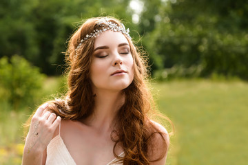 Redheaded young girl in the woods. Portrait of the bride in the Park