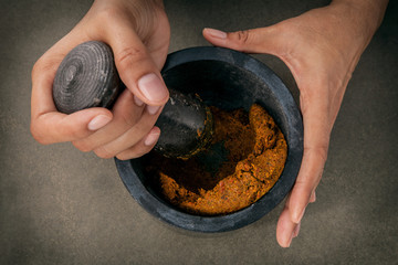 The Women hold pestle with mortar and and spice red curry paste