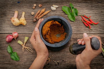 The Women hold pestle with mortar and spice red curry paste ingr