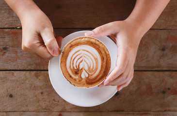 woman hand holding cup of coffee while resting in the cafe,top v