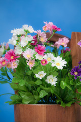 Bright and beautiful colors of plastic flowers in wood bucket on