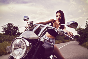 Plakat beautiful young woman posing with a motorcycle