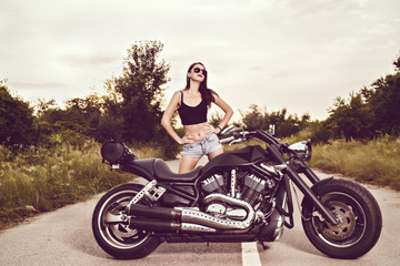 Obraz na płótnie Canvas beautiful young woman posing with a motorcycle