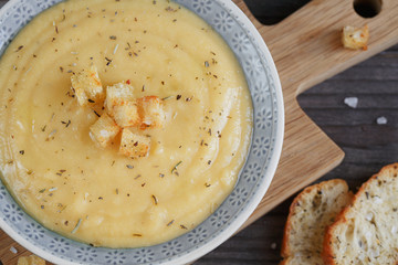 Bowl of zucchini and cauliflower cream soup on wooden table. Hea
