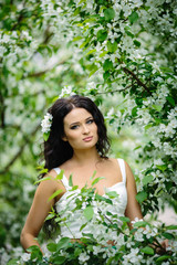 Young brunette woman portrait in blooming apple tree park