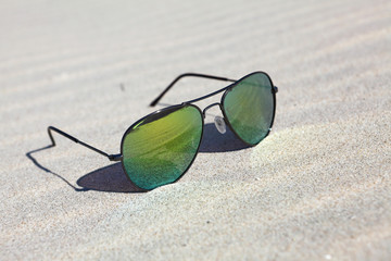Sunglasses on the sand , reflection of beach in sunglasses