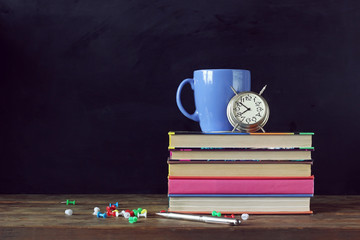 Back to school. Books, Cup and alarm clock on the table.
