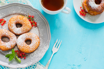 Homemade donuts in a gray plate with tea on a blue wooden background