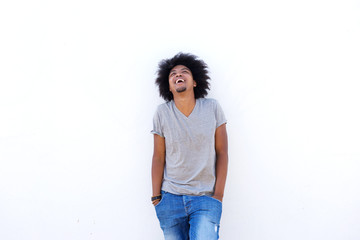 Laughing young man with hands in pockets looking up