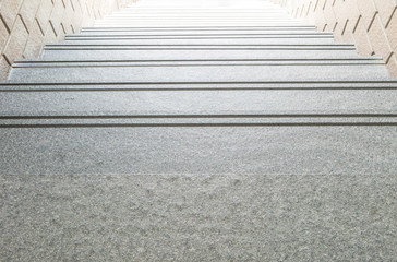 Closeup down step pattern of stone stair with blurred stone brick wall textured background under...