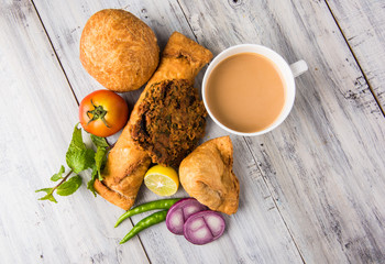 coriander vada or kothimbir vada, samosa, kachori, daal vada on brown wooden planks. indian...
