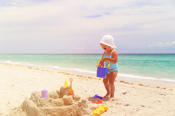 cute little girl play with sand on beach